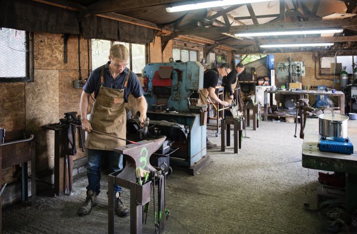 people in a forge workshop working on making a poker on a blacksmith experience