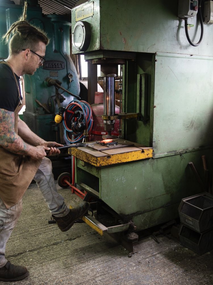 a blacksmith working at the hydraulic press