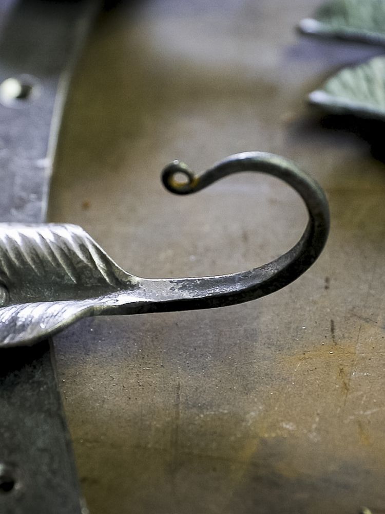 a close up of one of the leaf hooks on a coat rack made on a blacksmith experience
