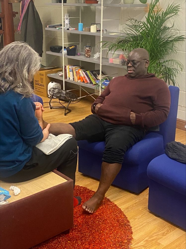 man having foot rubbed in reflexology class