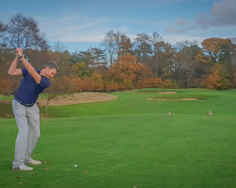 Man swinging a golf club on a golf course