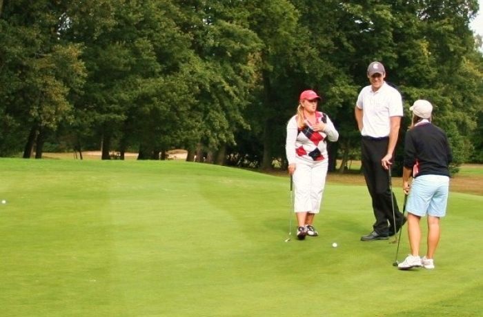 A male golfer standing with two female golfers