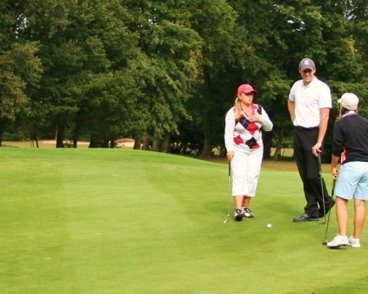 A male golfer standing with two female golfers
