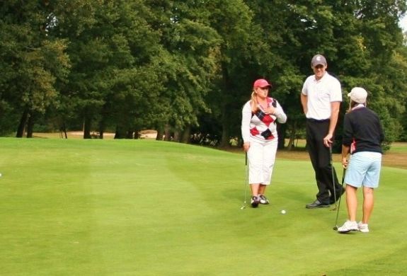 A male golfer standing with two female golfers