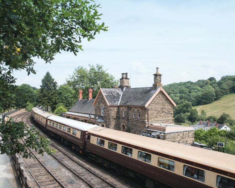a view of the northern belle vintage train carriages passing through a little village station