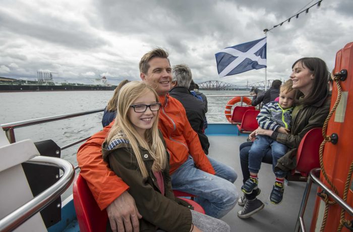 people sitting on the deck of a cruise boat on a daytime sightseeing cruise in scotland