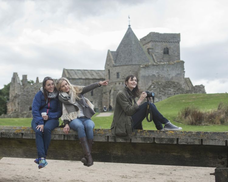 people posing for a photo in front of an old church on a daytime sightseeing cruise in scotland