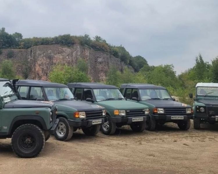 a fleet of land rover off road vehicles parked up ready a driving course in gloucestershire