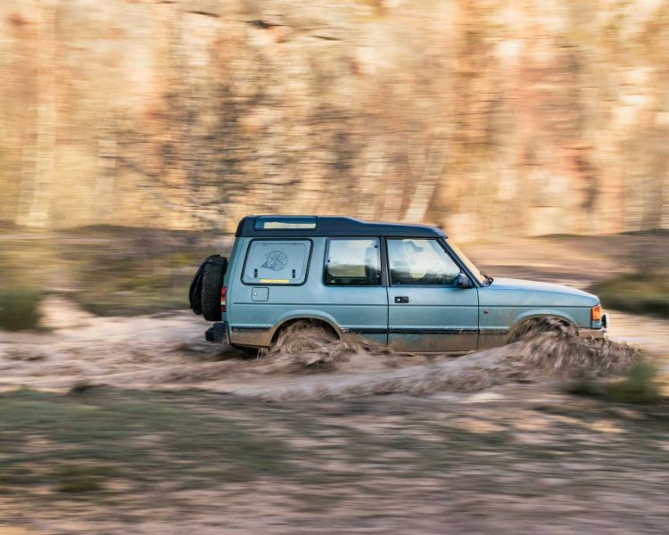a land rover off road vehicle driving through muddy water on a driving course in gloucestershire