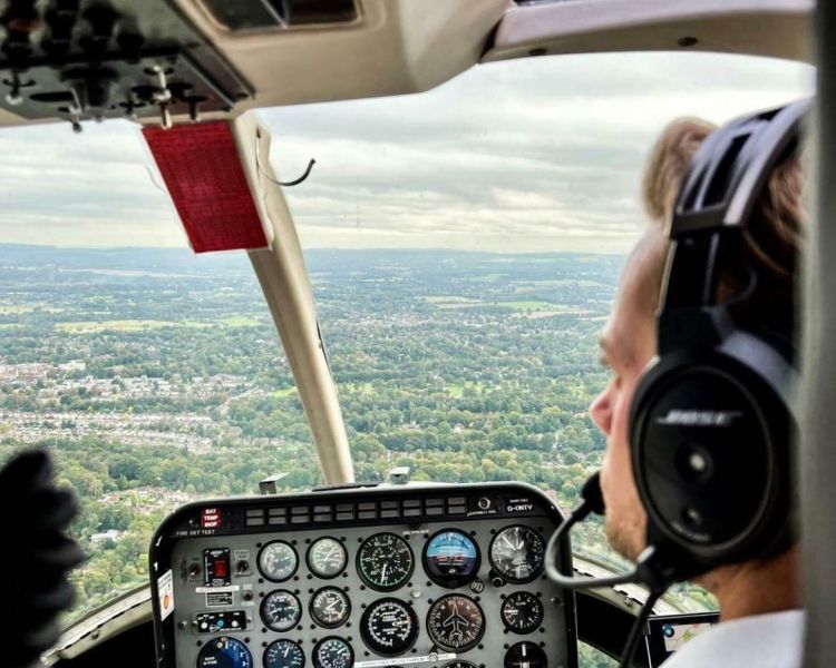 a photo of the pilot flying a helicopter looking out over the views below