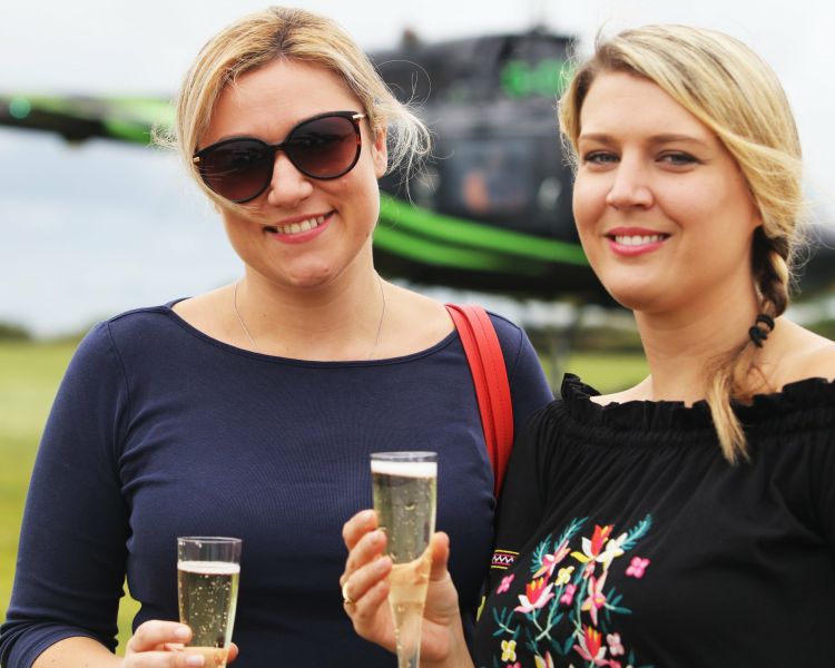 two women enjoying a drink of bubbly after a helicopter ride
