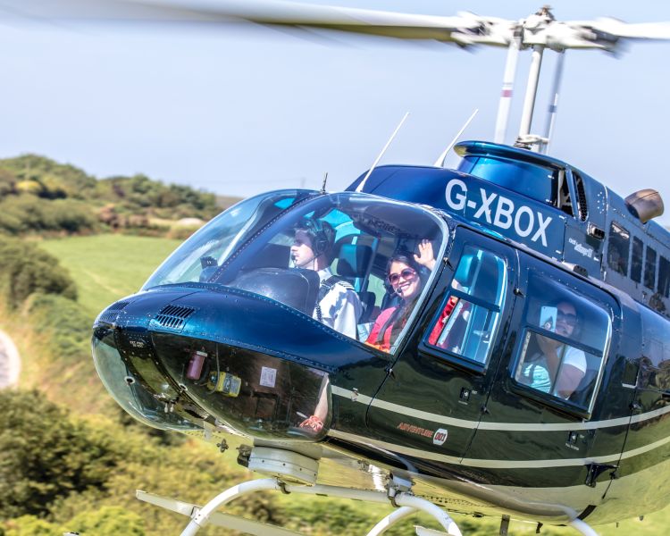 a black helicopter taking off for a helicopter tour with a person waving through the window