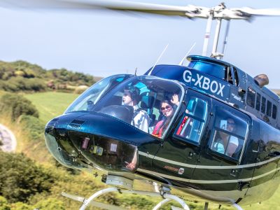 a black helicopter taking off for a helicopter tour with a person waving through the window