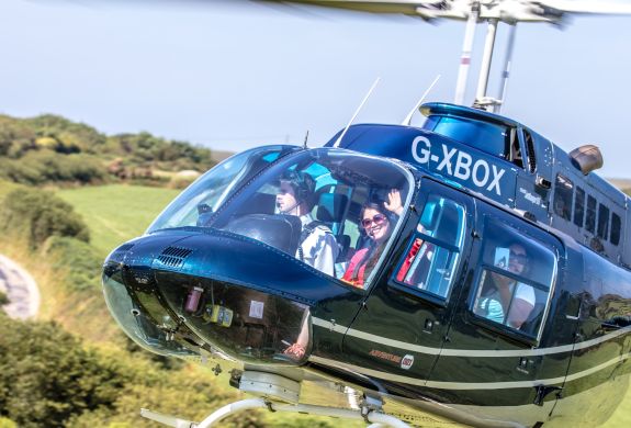a black helicopter taking off for a helicopter tour with a person waving through the window