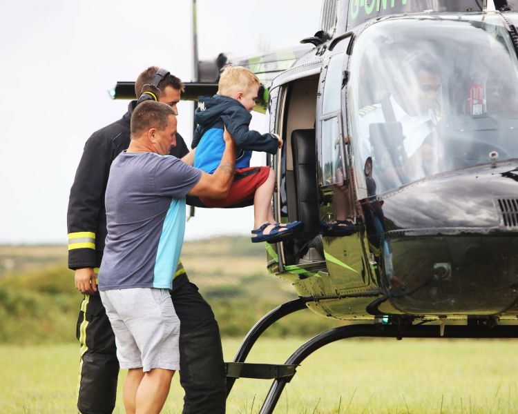 a man helping a child into a helicopter as part of a helicopter family experience