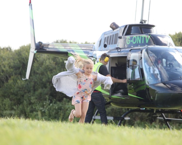 a helicopter getting ready for take off as a child is running out the way as part of a helicopter experience day