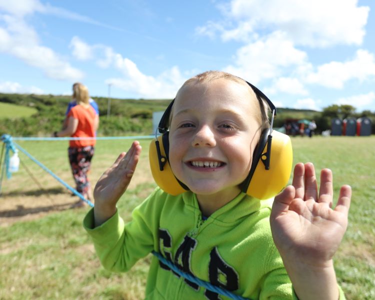 a photo of a happy child wearing yellow ear defenders as part of a helicopter experience day