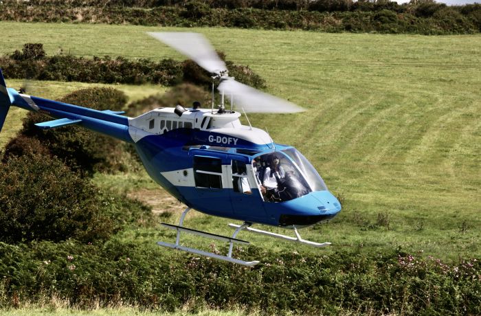 a blue and white helicopter flying over fields as part of a chopper experience