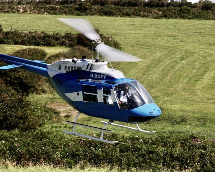 a blue and white helicopter flying over fields as part of a chopper experience