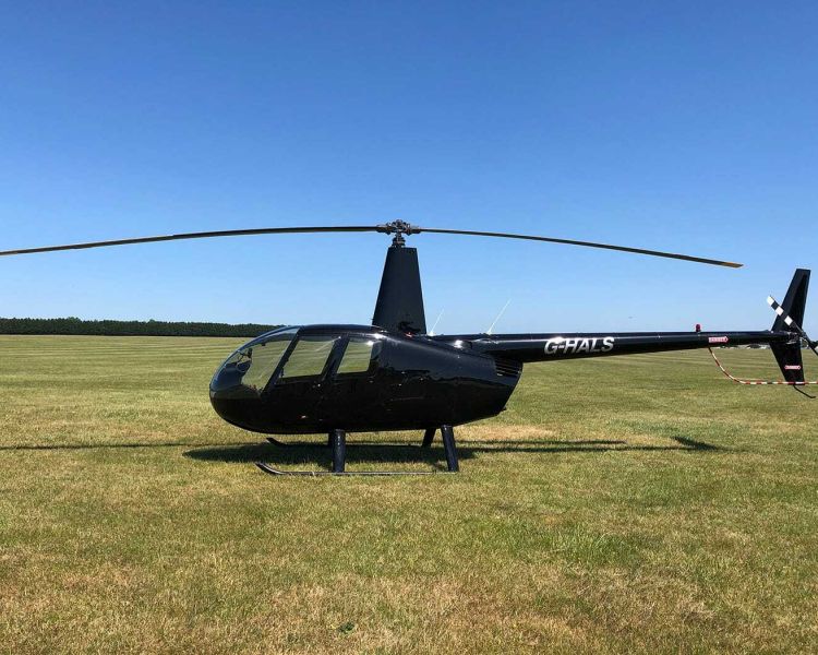 a black helicopter in a field against a blue sky as part of a national helicopter flying lesson
