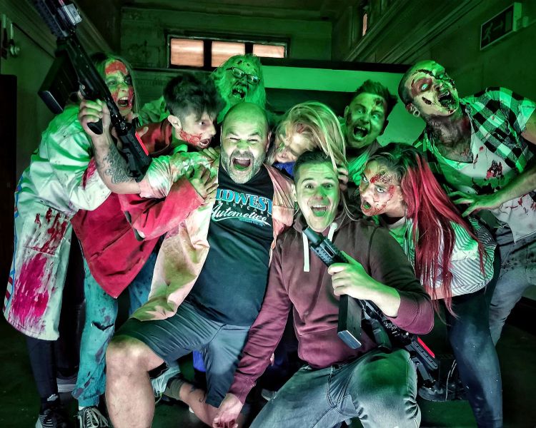 visitors posing with zombies covered in blood as part of a zombie survival experience