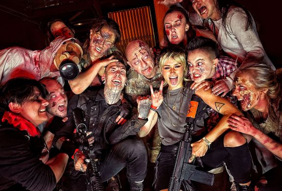 visitors posing for photo with zombies covered in blood as part of a zombie survival experience