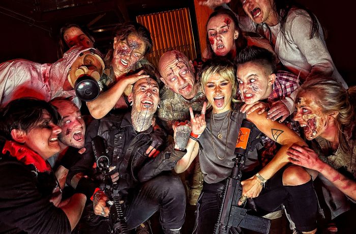 visitors posing for photo with zombies covered in blood as part of a zombie survival experience