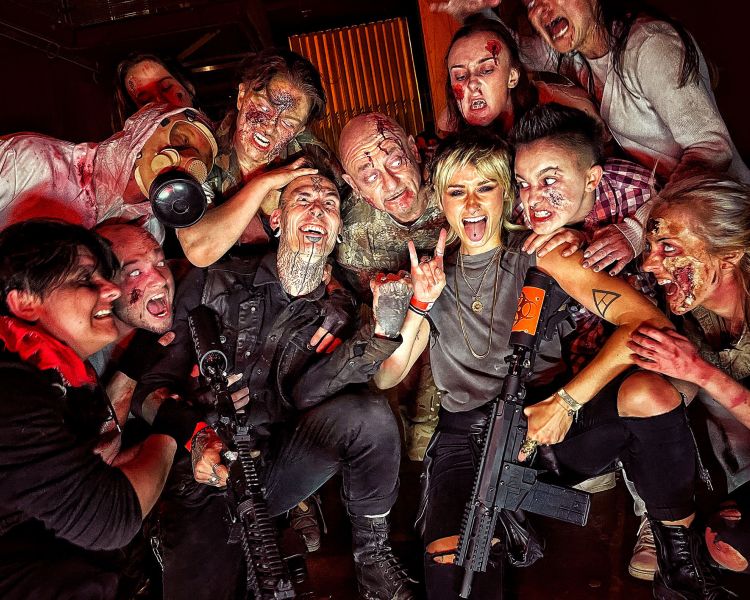 visitors posing for photo with zombies covered in blood as part of a zombie survival experience