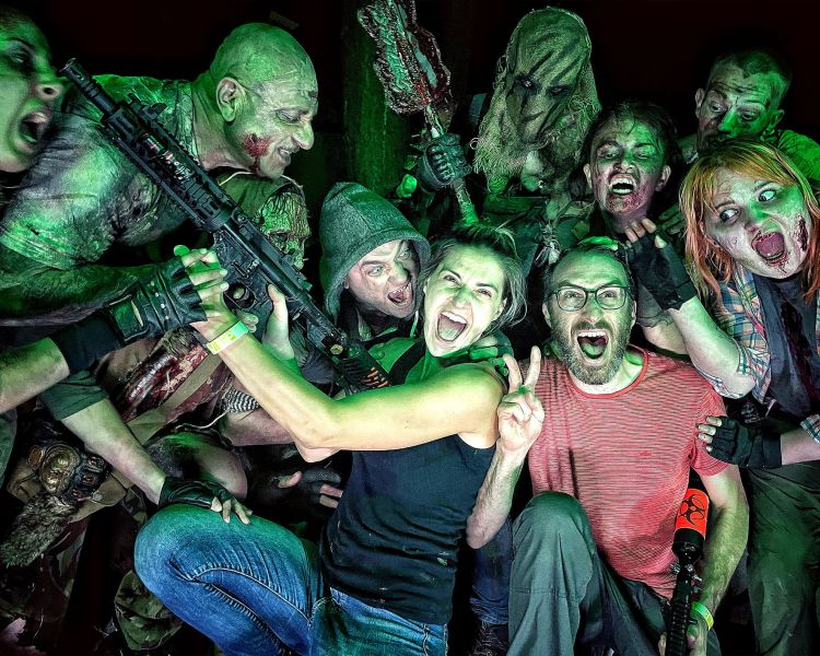 two people posing with zombies s part of a zombie survival chasing experience available nationwide