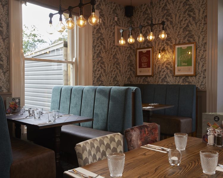 an inside shot of the holmfield arms showing a dining area of tables and booths decorated in a charming country style