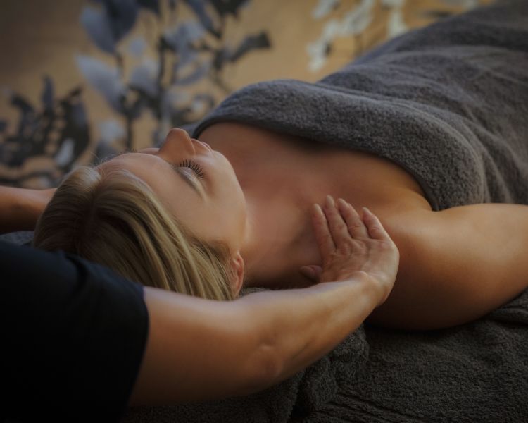 Woman lying on treatment bed having a shoulder massage at the spa hotel dunston hall in norfolk