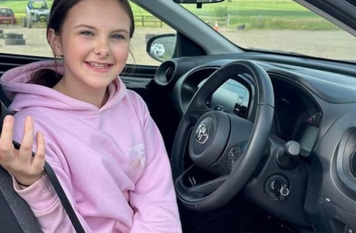a young girl in the drivers seat of a car on a junior driving experience