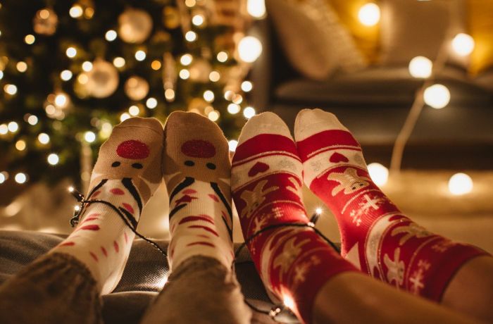 Feet in christmas socks with christmas tree in background covered in lights