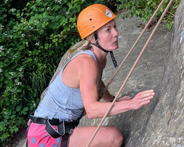 A woman climbing with foliage in the background Climbing Exp Hatt Adventures