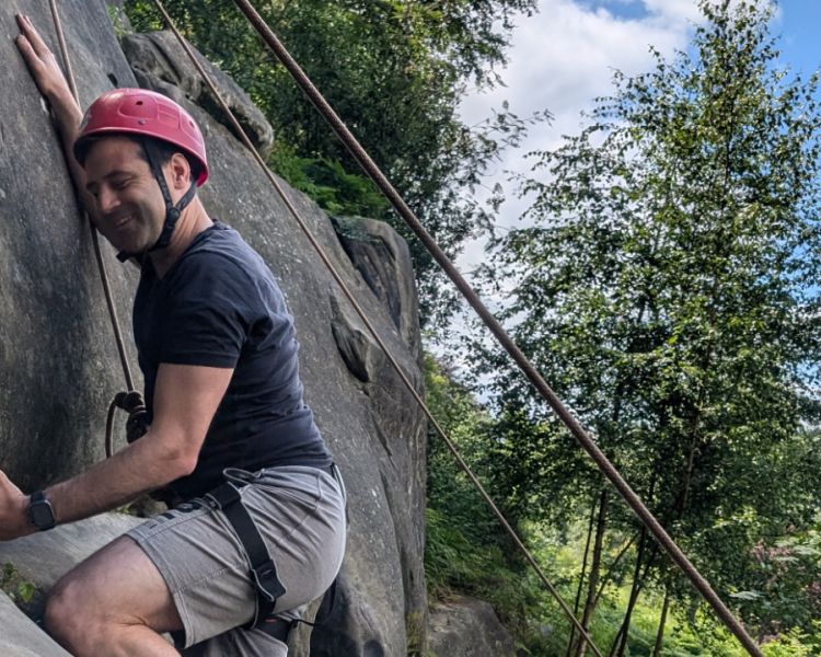 A man climbing with trees in the background Climbing Exp Hatt Adventures