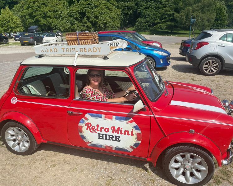a woman in the drivers seat of a classic red mini cooper on a self drive road trip