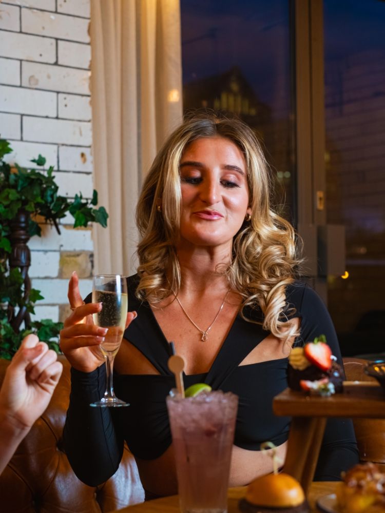 a woman holding a drink at afternoon tea