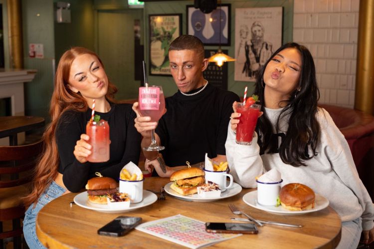 3 guests posing with cocktails and burgers