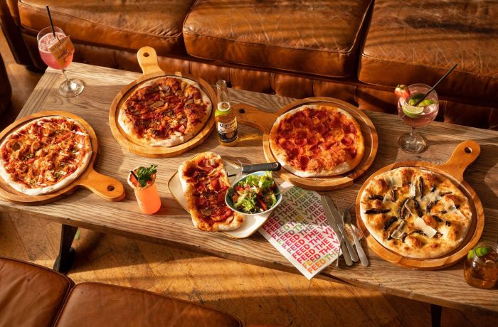 an assortment of 4 pizzas on a coffee table