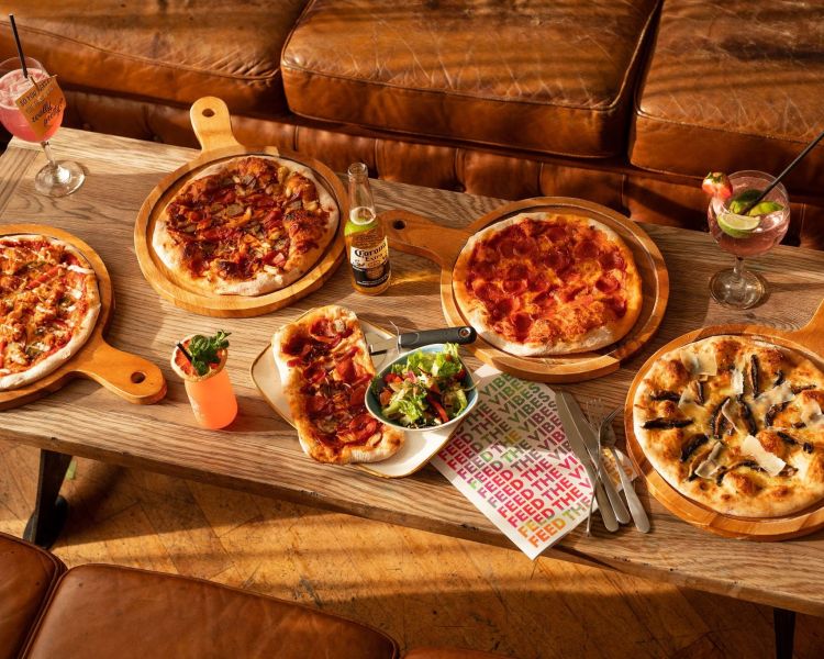 an assortment of 4 pizzas on a coffee table