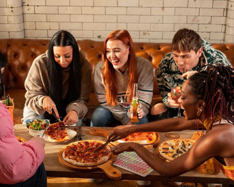 a group of 5 eating pizza and chatting