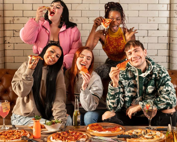 a group of 5 eating pizzas