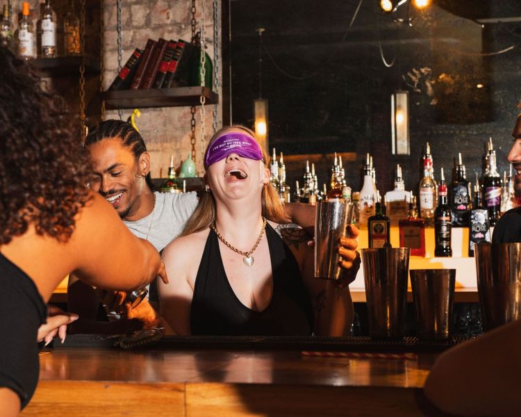 a bartender making drinks while blindfolded while two other bartenders observe