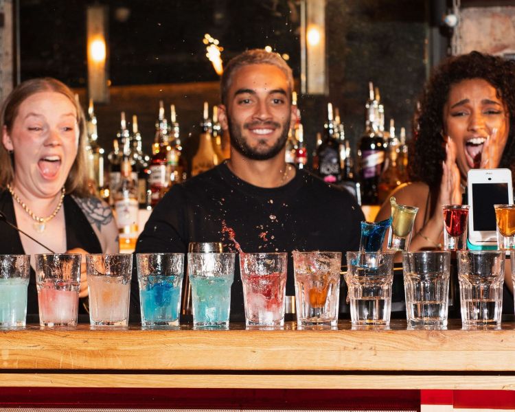3 bartenders looking at a line of cocktails with excitement 2