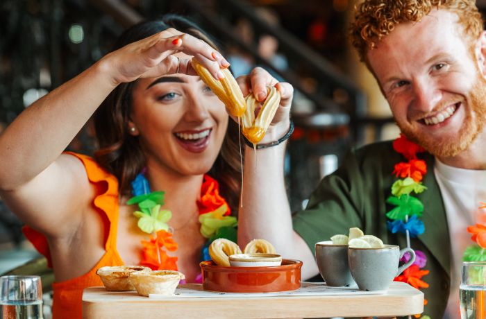 a man and a woman enjoying an afternoon tea with cuban inspired treats like churros