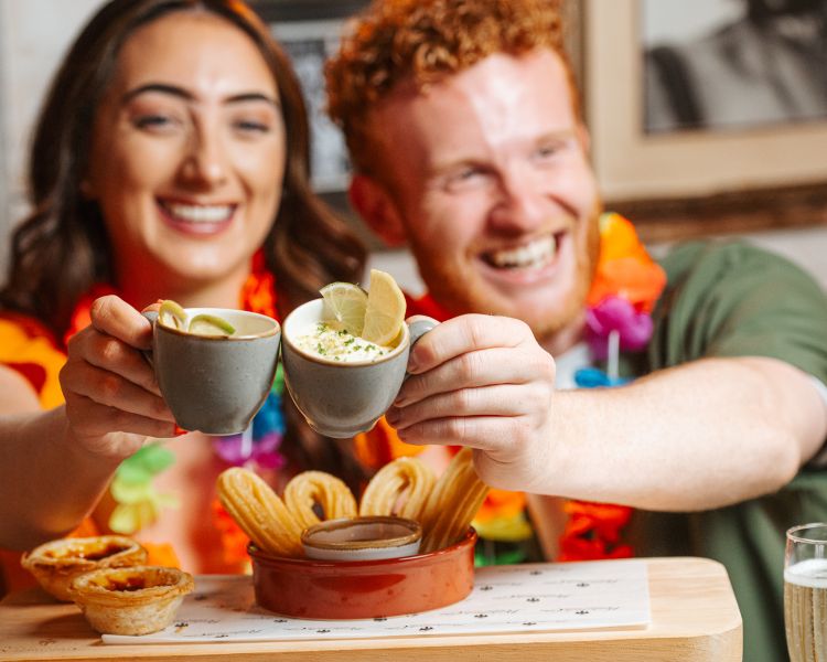 a man and a woman enjoying an afternoon tea with cuban inspired sweet treats