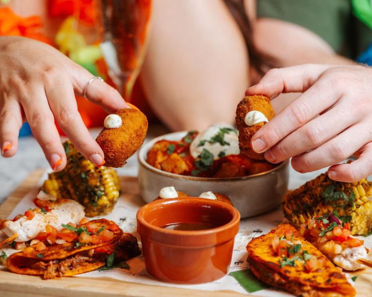 a man and a woman enjoying an afternoon tea with cuban inspired savoury food
