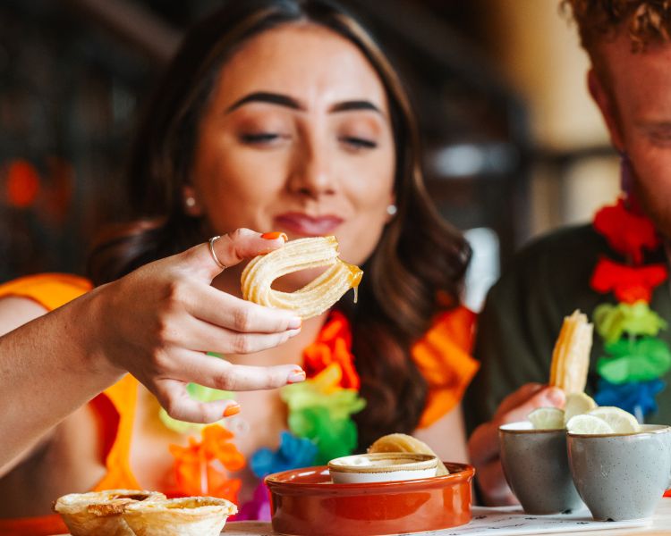a man and a woman enjoying an afternoon tea with cuban inspired treats like churros