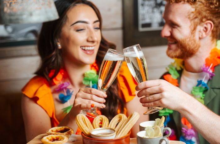 a man and a woman enjoying a glass of prosecco with cuban inspired afternoon tea