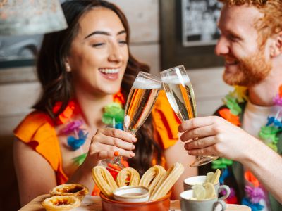 a man and a woman enjoying a glass of prosecco with cuban inspired afternoon tea